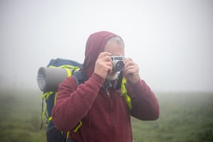older man photographer taking picture outside on hike