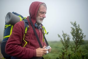 older man walking in the rain with camera