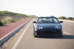 older couple driving down highway in convertible car