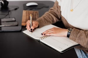 older woman sitting at desk writing in journal