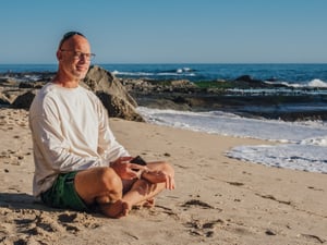 older man taking a break at the beach meditating