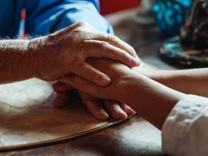 older man holding hands with woman caring