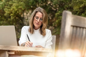 woman writing outside on picnic table