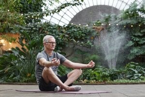 older man meditating in garden