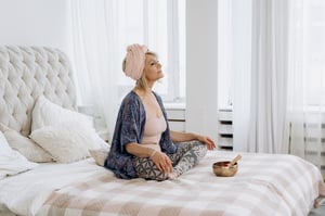 Woman meditating on her bed in the morning
