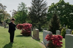 older woman grieving looking at tombstone