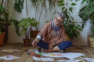 older woman painting sitting on floor