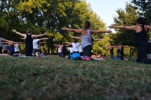 group of women practicing Pilates outdoors in a grassy park