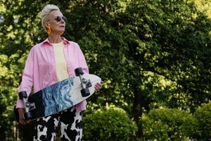 older woman with skateboard wearing sunglasses outside