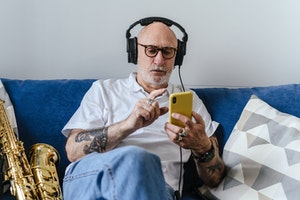older man sitting on couch listening to music