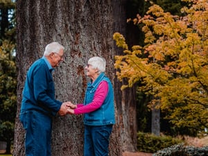 Happy retired older couple holding hands outside in the park