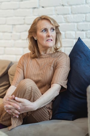 Older woman sitting nervously ono couch_anxiety