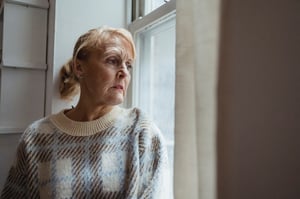 older woman with depression looking outside of window