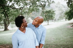 Happy retired couple looking at each other and holding hands outdoors