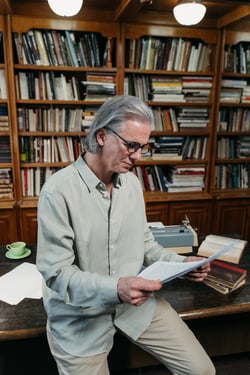 older man reading at a desk in office