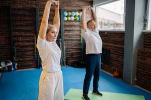 older man and woman stretching in studio gym