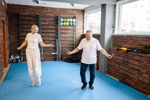 senior couple exercising together jumping rope in indoor studio gym