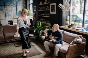 older man playing guitar and singing at home for wife