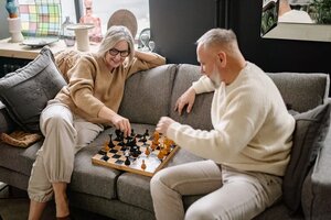 older couple playing chess together on the couch