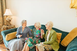 three older woman sitting together on sofa talking and laughing