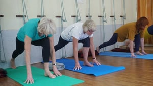 three older women practicing yoga stretching at an indoor studio