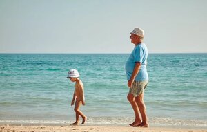 grandfather walking on the beach with grandson on vacation