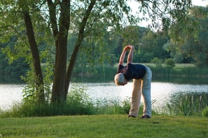 older man stretching outside in a park